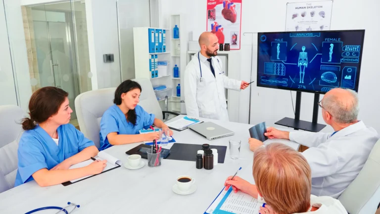 mature-medical-physician-explaining-treatment-nurses-healthcare-seminar-pointing-digital-monitor-clinic-herapist-discussing-with-colleagues-about-disease-medicine-professional